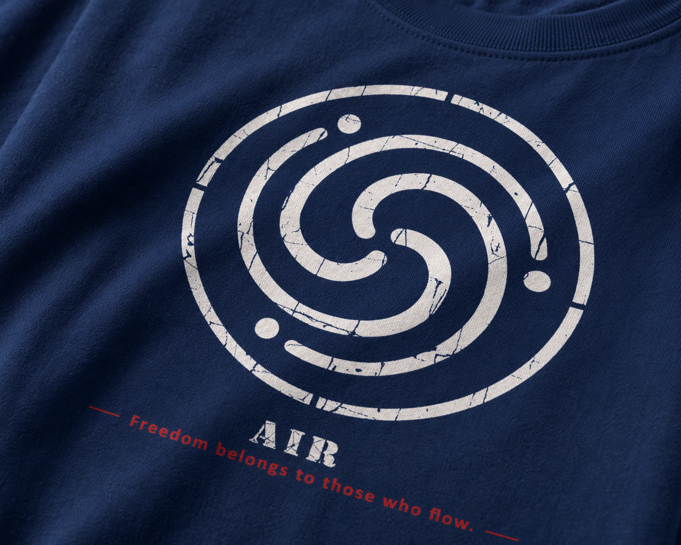 Close-up of a navy blue t-shirt featuring a distressed white spiral graphic with the word 'AIR' and the quote 'Freedom belongs to those who flow.' printed below in red and white.